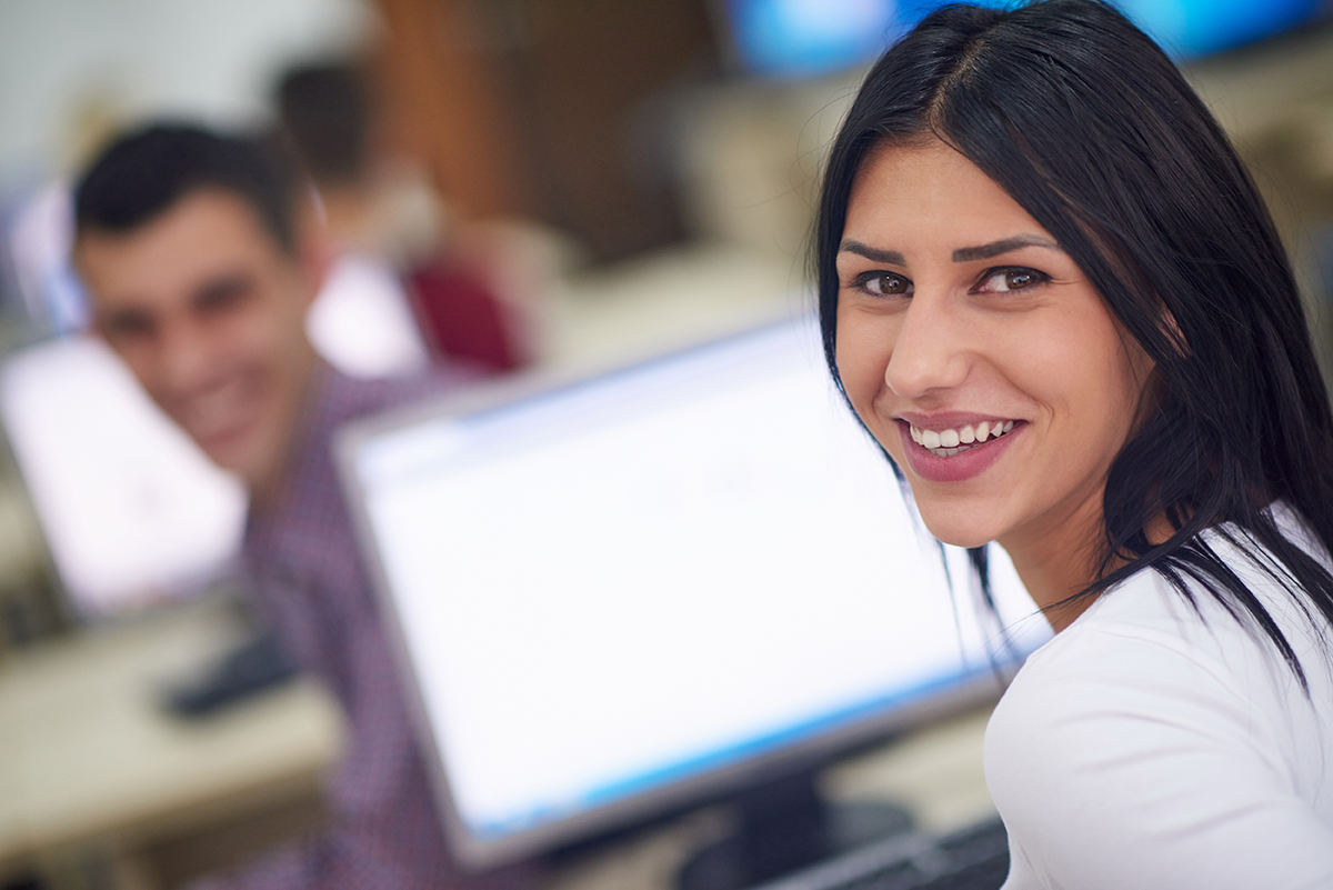 Woman at a computer smiling at the camera